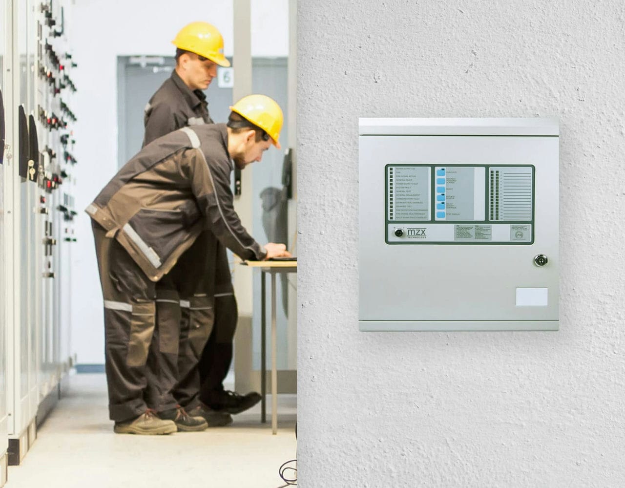 A fire detection unit mounted on a wall, with two maintenance workers fixing something in the background